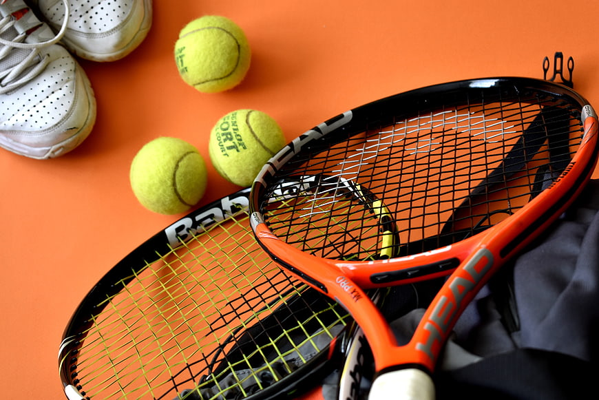 Tennis Equipment Flat Lay with Rackets, Balls, and Shoes on Orange Background