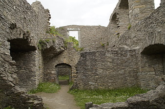 Ancient Stone Castle Ruins With Arched Doorway And Overgrown Grass