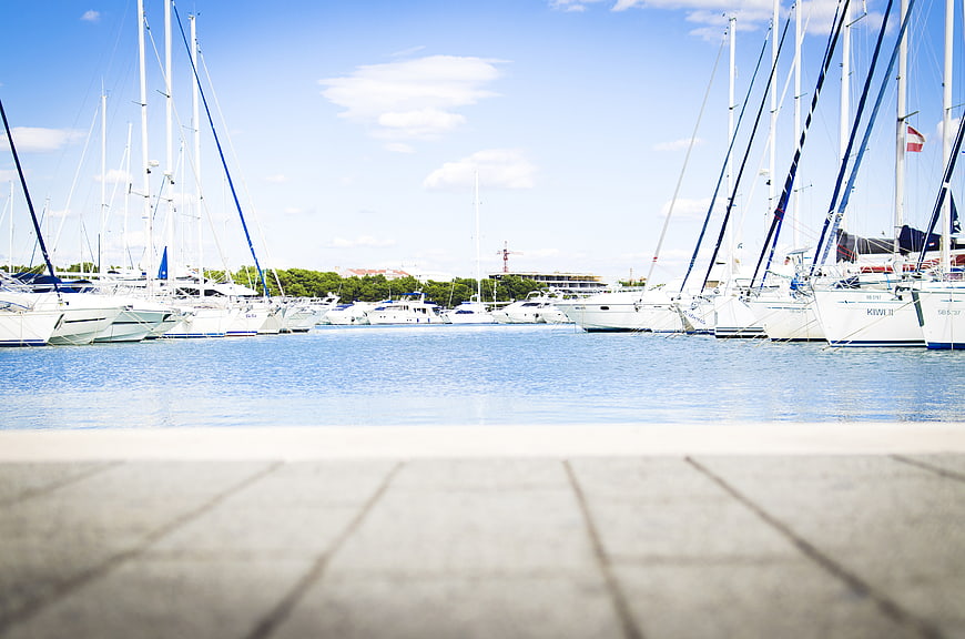 Sailboats docked in a sunny marina with blue sky