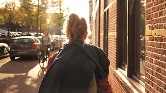 Woman Walking on Sunny Street with Brick Building