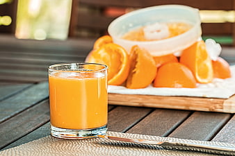 Fresh Orange Juice on Wooden Table with Squeezed Oranges