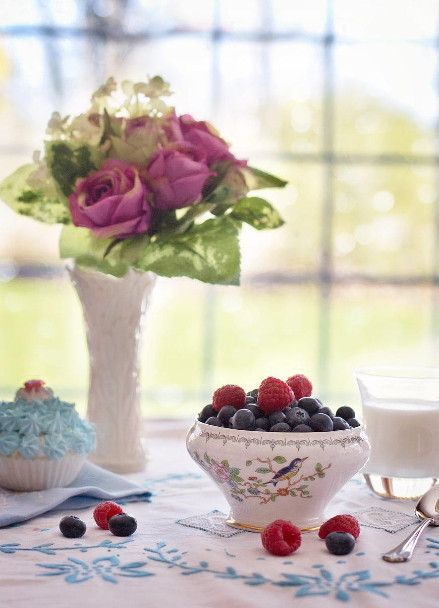 Fresh berries in vintage bowl with flowers and milk