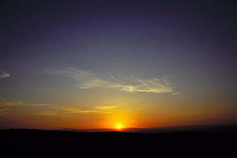 Vibrant sunset over dark forest silhouette landscape