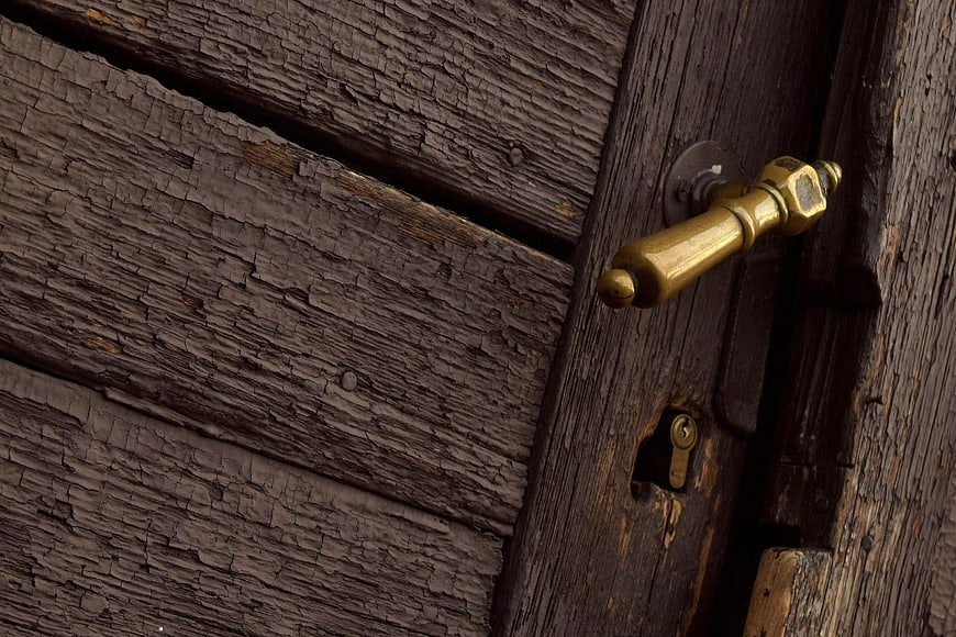 Close-up of vintage brass door handle on weathered wood