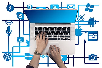 Top view of hands typing on laptop with social media icons