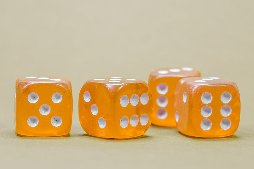 Four Orange Dice Showing High Numbers on Beige Background