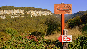Wooden hiking trail signpost in Italian mountain landscape