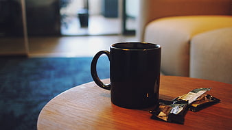 Black coffee mug on wooden table in hotel room