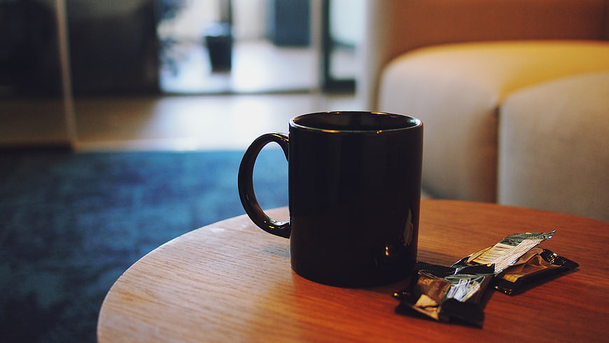 Black coffee mug on wooden table in hotel room