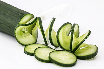 Fresh Cucumber Slices and Spiral Peel on White Background