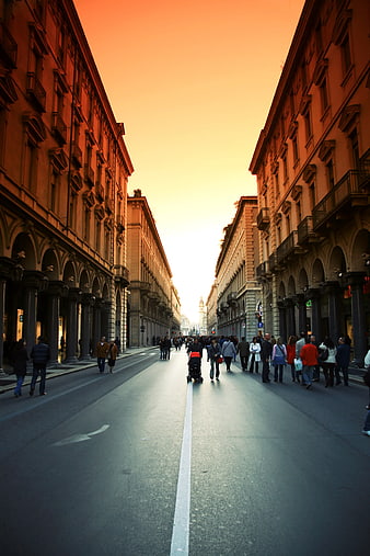 Pedestrians walking on city street under dramatic orange sunset sky