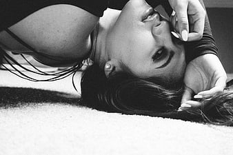 Black and white portrait of a woman lying down with hand near face