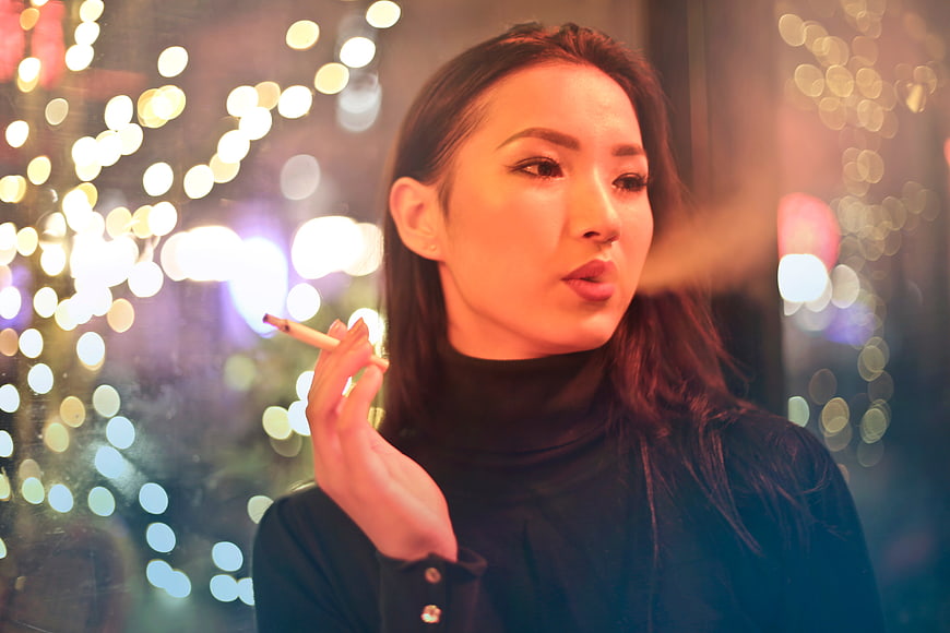 Asian woman smoking cigarette with bokeh lights background
