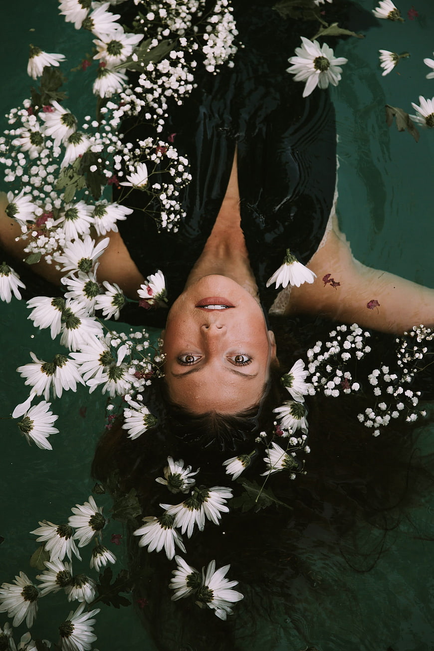 Woman Floating Upside Down in Water with White Flowers