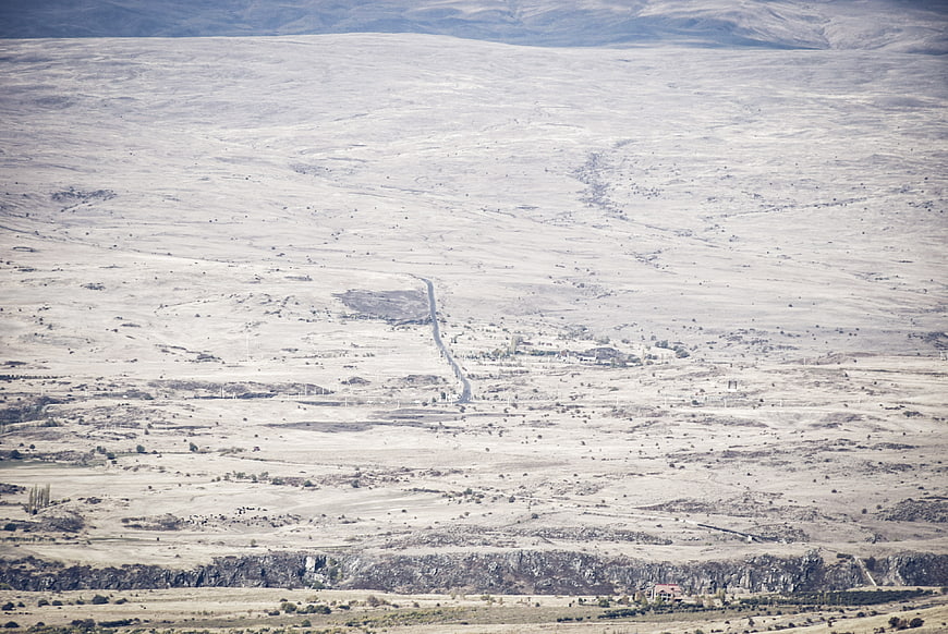 Vast arid landscape with winding road and distant mountains