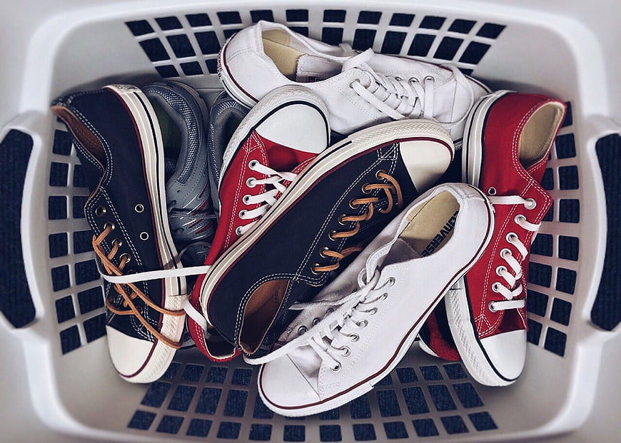 Assorted Unpaired Sneakers in White Laundry Basket