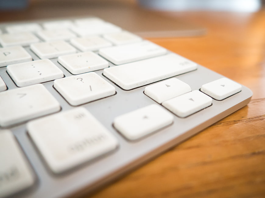 Close-up of white computer keyboard on wooden desk