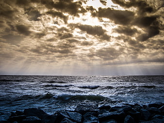 Dramatic Seascape with Sunbeams Breaking Through Clouds Over Rocky Shore