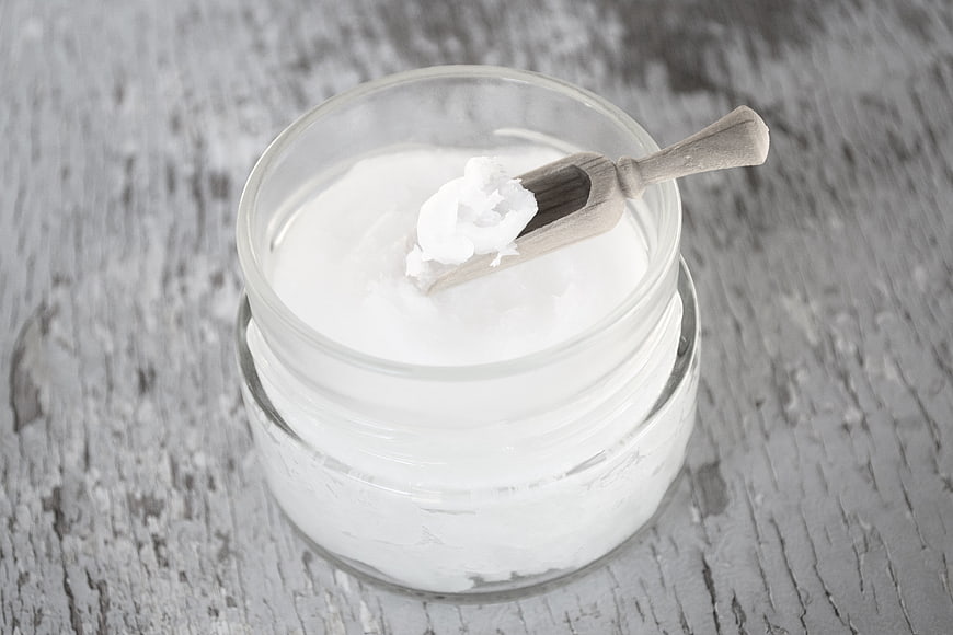 Coconut Oil In Glass Jar With Wooden Spoon On Rustic Wood