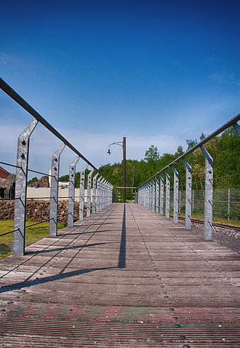 Modern wooden bridge with metal railings and blue sky