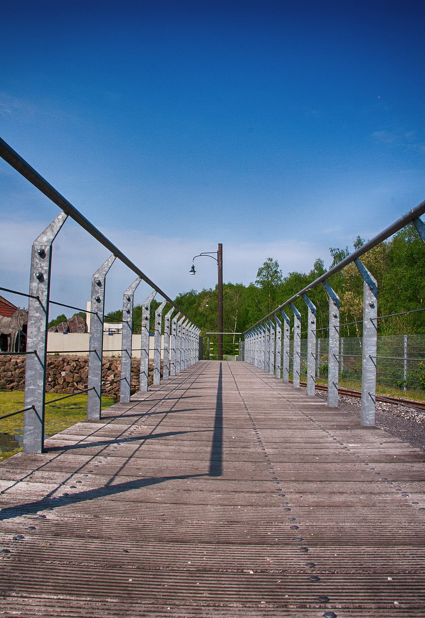 Modern wooden bridge with metal railings and blue sky