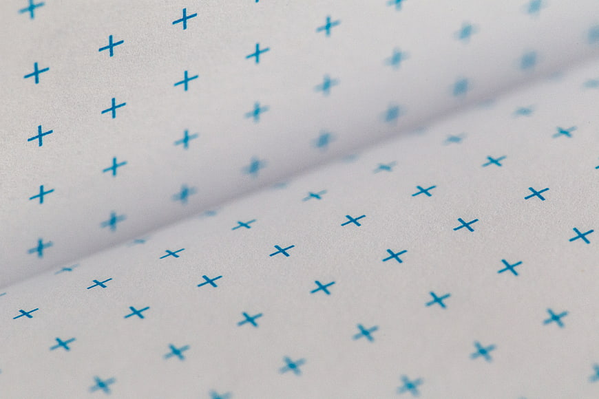Close-up of white paper with blue plus sign pattern