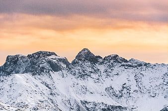 Snowy Mountain Peaks at Sunset with Orange Sky