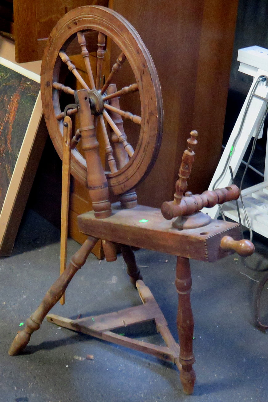 Vintage wooden spinning wheel in rustic workshop setting