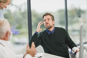 Upset male patient arguing with doctors in clinic