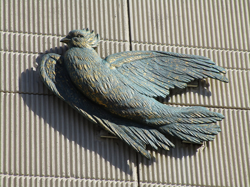 Bronze dove sculpture mounted on textured wall
