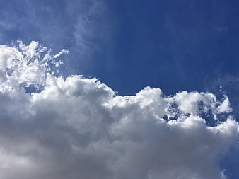 Dramatic white cumulus clouds against deep blue sky