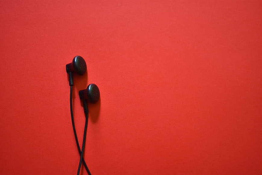 Black Earphones on Vibrant Red Background with Copyspace