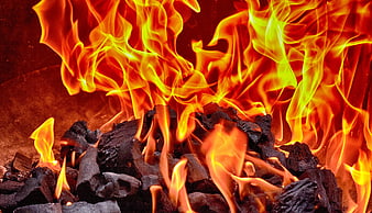 Close-up of burning charcoal briquettes with bright orange and yellow flames