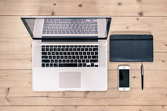 Flat lay of laptop, smartphone, and notebook on wooden desk