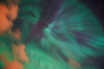 Green and purple aurora borealis with stars and clouds