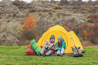 Happy couple camping in yellow tent with coffee