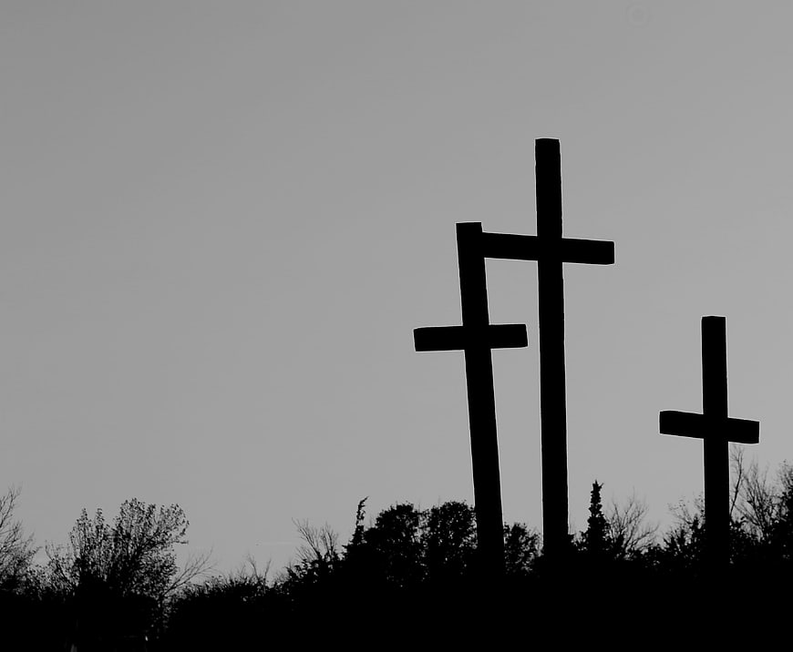 Three Silhouetted Wooden Crosses Against Gray Sky