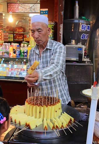 Chinese street vendor preparing skewered cake snacks