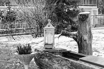 Rustic wooden water fountain with lantern in snowy garden