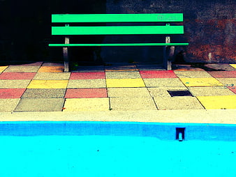 Vibrant Green Bench on Colorful Tiles Near Blue Pool
