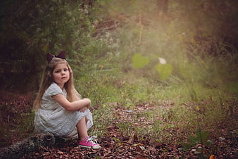 Young girl sitting on a log in a misty forest
