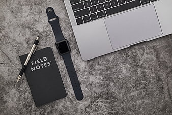 Minimalist workspace with laptop, smartwatch, and notebook