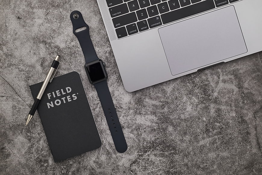 Minimalist workspace with laptop, smartwatch, and notebook