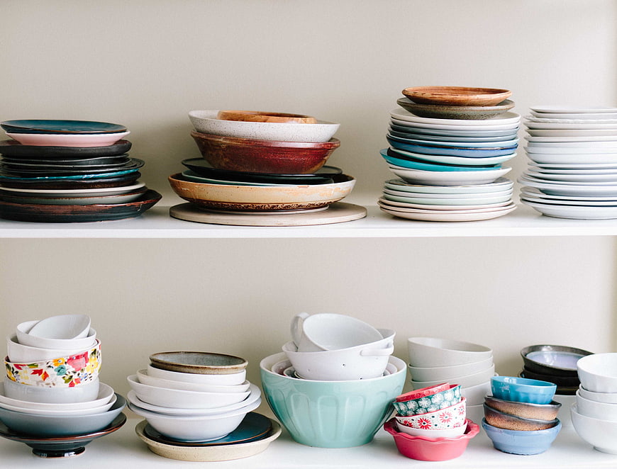 Colorful Stacked Ceramic Bowls and Plates on White Shelves