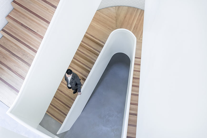 High angle view of man walking down modern wooden spiral staircase