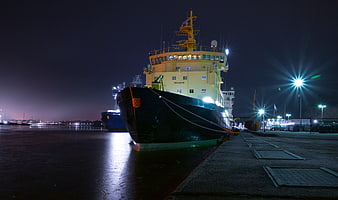 Large cargo ship docked at night in harbor