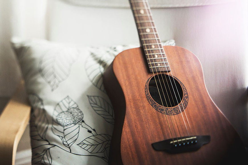 Acoustic Guitar on Chair with Leaf Pattern Pillow