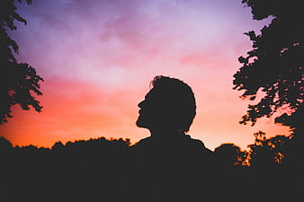 Silhouette of Man Looking Up at Colorful Sunset Sky