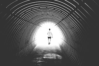 Man Walking Through Dark Tunnel Towards Bright Light