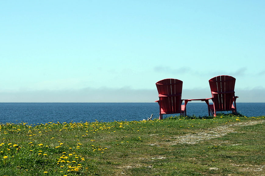 Two Red Adirondack Chairs Overlooking Ocean Horizon